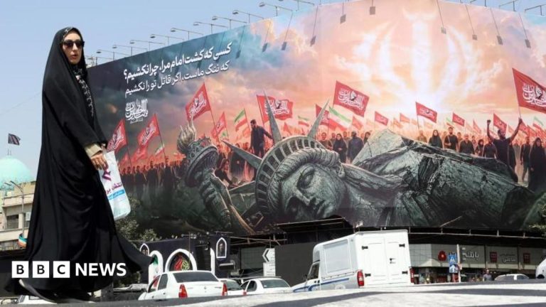 A veiled Iranian woman walks past an anti-US billboard at Enghelab Square in central Tehran