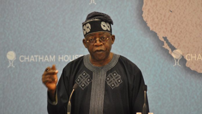 Nigerian President Bola Tinubu speaks at a lectern, gesturing with one hand