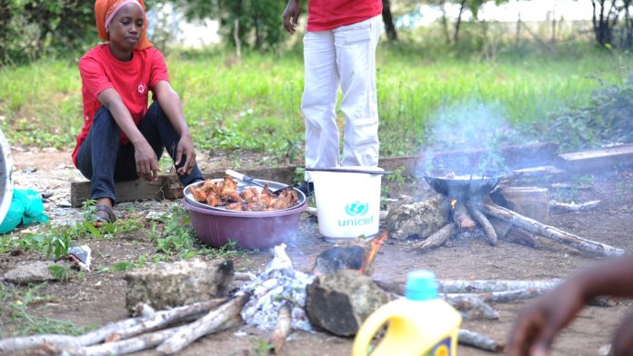 Volunteers prepare food over an open fire during a community health outreach in Kenya