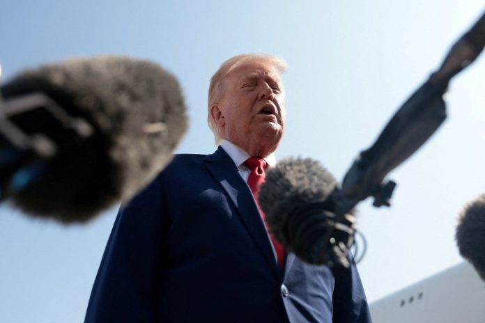 US President Donald Trump speaks to reporters surrounded by microphones