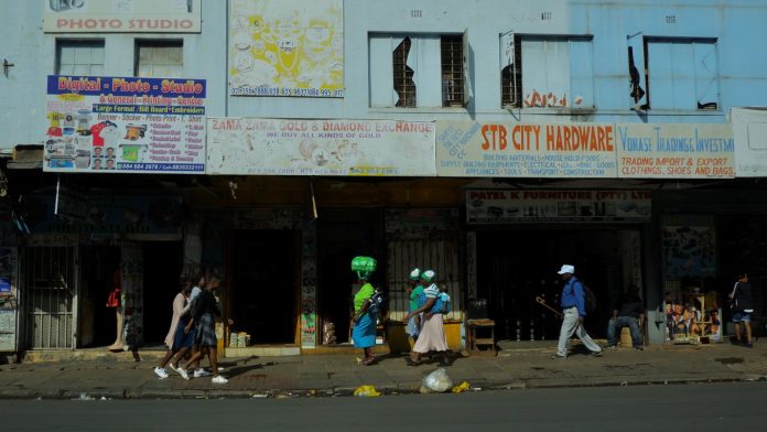 Pedestrians walk past shopfronts on a busy Johannesburg pavement
