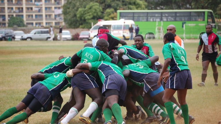 Kenyan club rugby players bind together contesting possession on a grass pitch