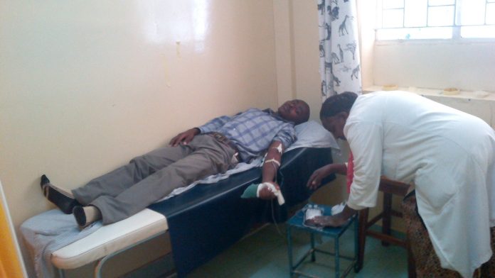 A health worker attends to a man lying on a couch in a Kenyan clinic room