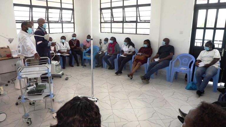 Patients sit waiting on chairs in the open waiting area of a Kenyan health facility