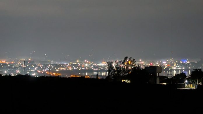 Lights of Kisumu city spread out below a dark hillside at night