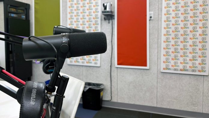 A studio microphone and headphones in a podcast recording booth (file photo)