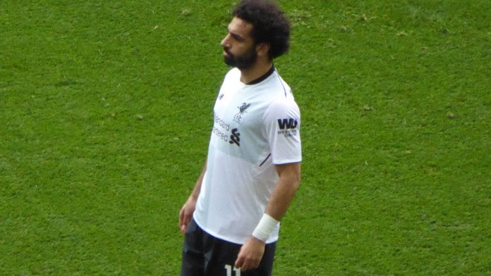 Mohamed Salah stands on the pitch in a Liverpool away kit during a match