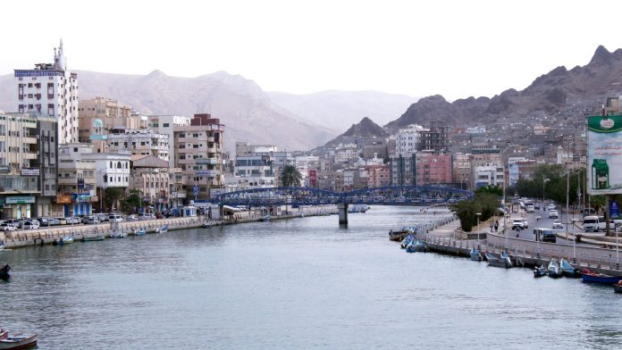 Buildings line a calm inlet at Mukalla on Yemen’s southern coast, with hills behind