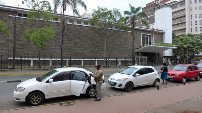 The exterior of the Nairobi City County Assembly building with cars parked outside