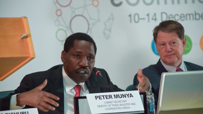 Kenyan politician Peter Munya speaks at a conference table beside a name plate