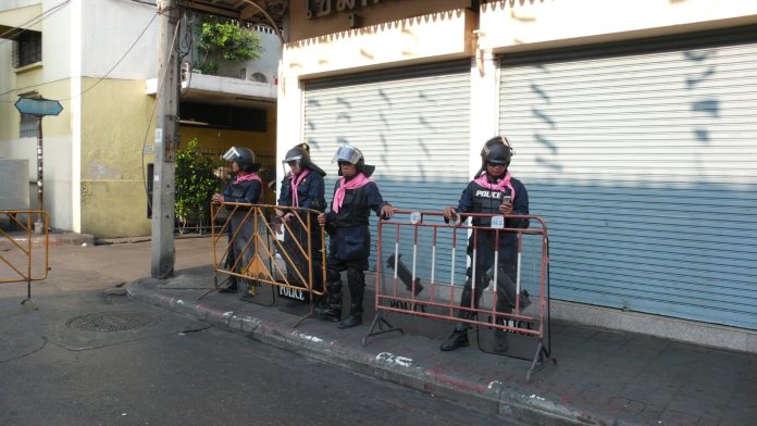 Royal Thai Police officers standing on a street beside parked vehicles