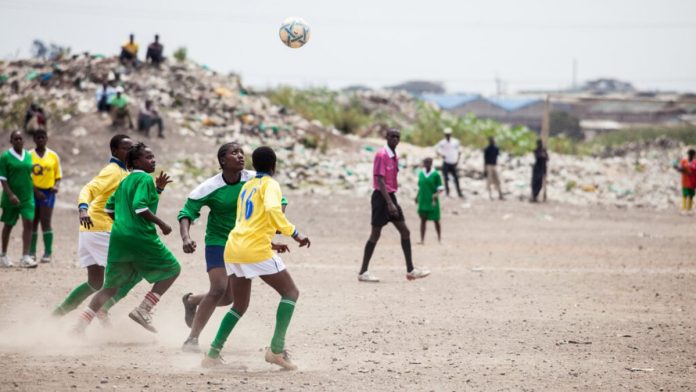 Kibera Girls Soccer Academy players contest a header on a dusty Kibera pitch