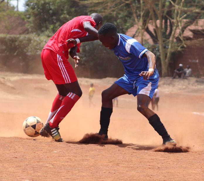 Young footballers playing on a dirt pitch in Kibra