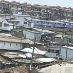 Tin-roofed houses in Kibera, Nairobi, with apartment blocks behind